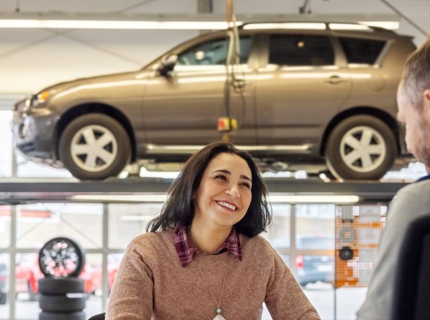 Woman talks with salesperson at a car shop.